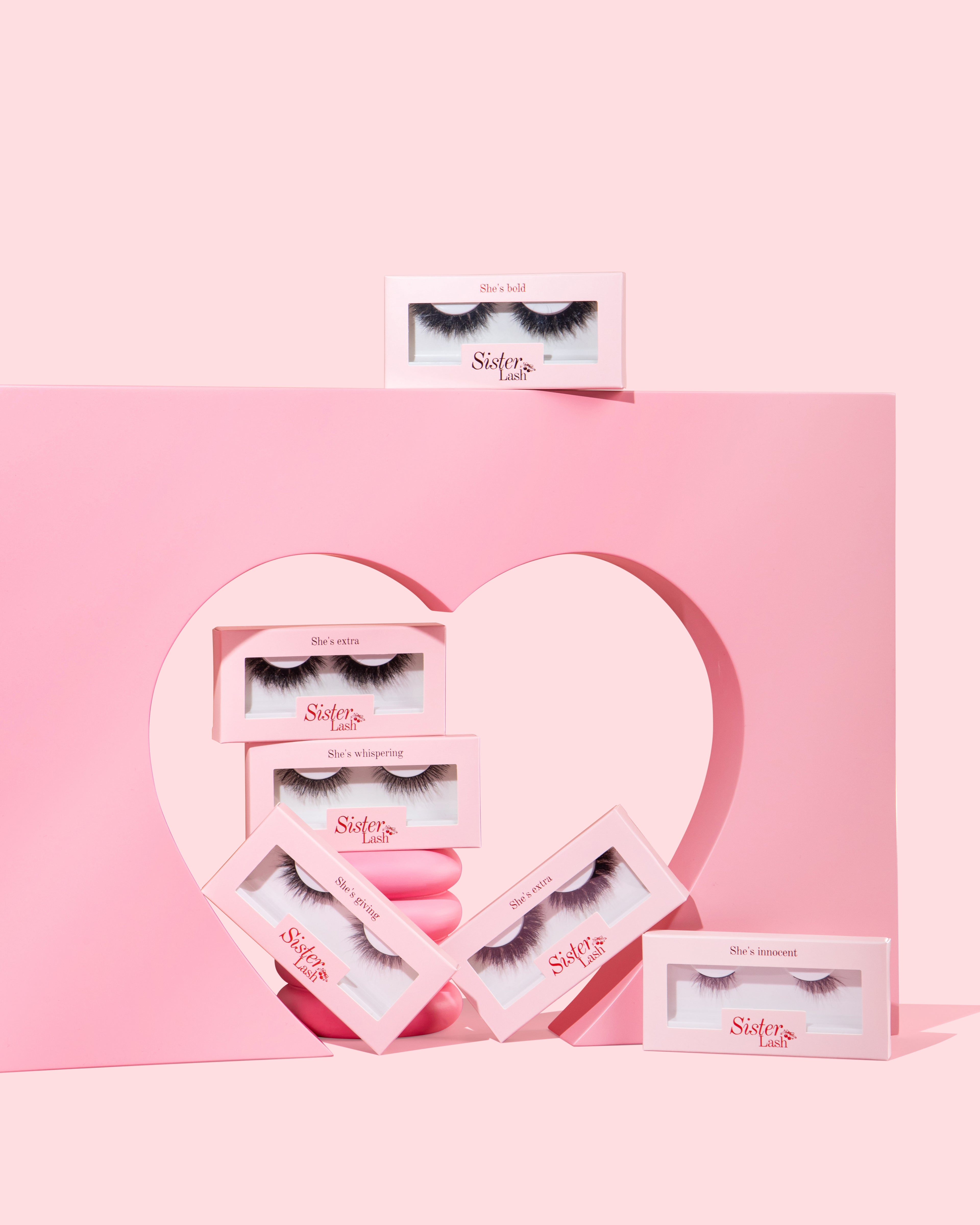 Set of false eyelashes in pink packaging with a heart design on a pink background