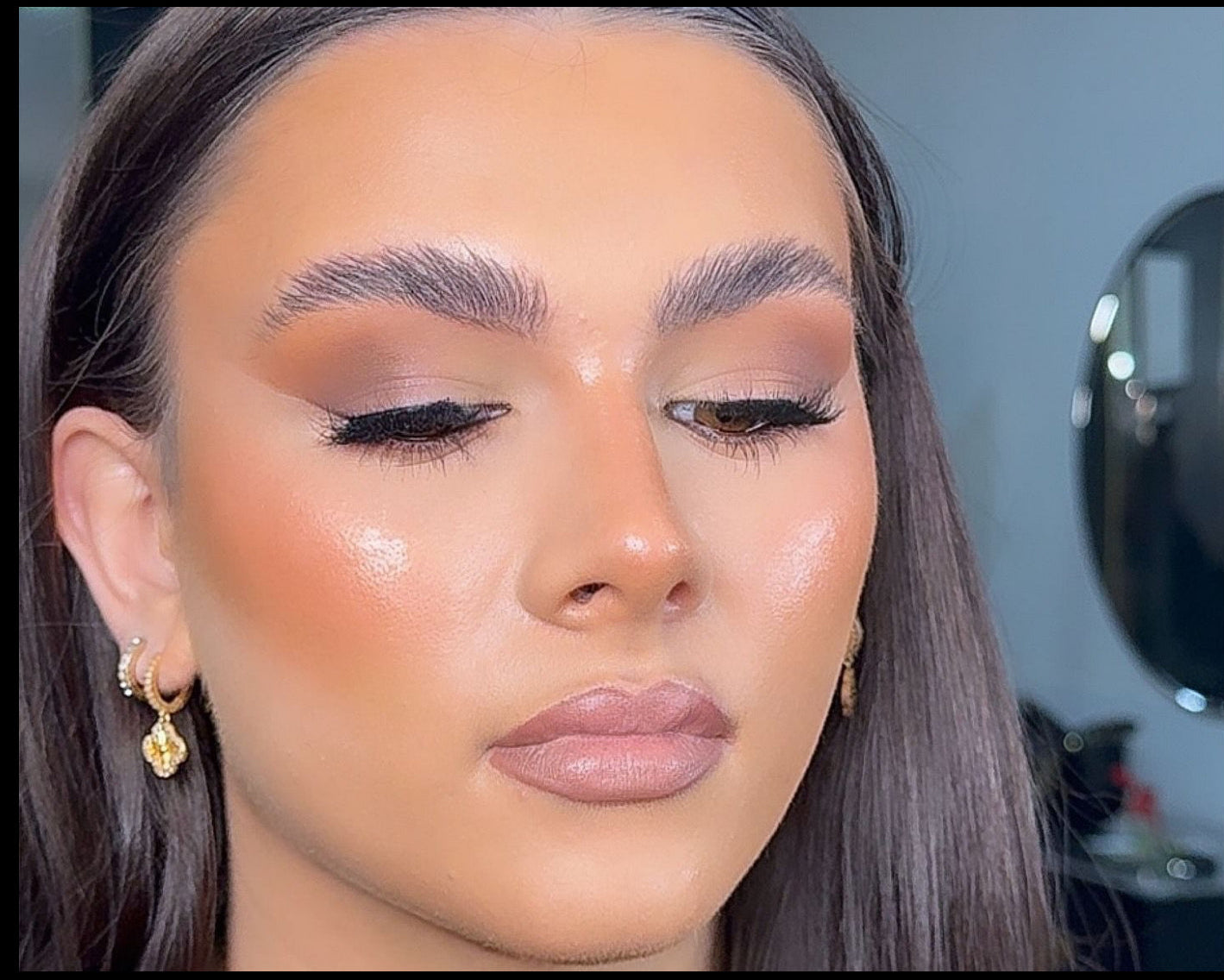 Close-up of a person with makeup, including eyeshadow and eyeliner, in an indoor setting.